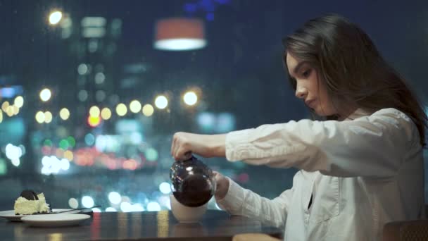 Meisje giet thee uit de ketel en het zittend in een café drinkt. — Stockvideo