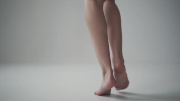 Сексуальные ноги молодой девушки. Девушка идет на цыпочках на светлом фоне. вид сзади — стоковое видео