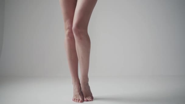 Kadın bacaklarını kapat. Kız tiptoes yalınayak ayak ayak değişen standları. — Stok video