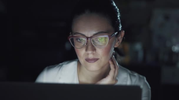 Zakenvrouw werken op kantoor laat in de avond. weerspiegeling van het computerscherm met een bril. — Stockvideo