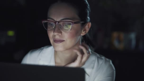 Ritratto di una donna d'affari che lavora al buio su un portatile. riflessione dello schermo con occhiali — Video Stock
