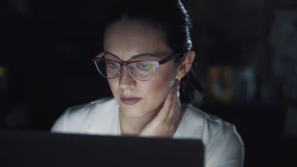 Деловая женщина в очках, работающая на ноутбуке в темном офисе — стоковое видео