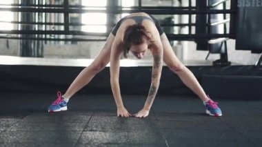 genç kadının germe egzersiz önce spor salonunda yapması. boks halka arka plan üzerinde kız ısıtır