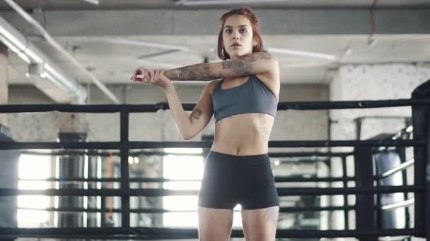 Chica moderna haciendo estiramiento en el gimnasio en el fondo del anillo de boxeo — Vídeos de Stock