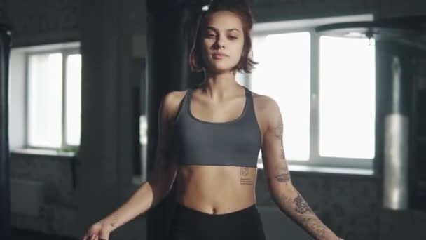 Porträtt av en kvinnlig idrottare i gymmet. ung flicka gör cardio hoppa rep — Stockvideo
