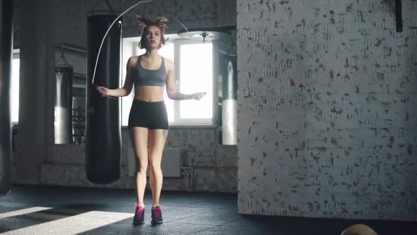 A rapariga treina no ginásio de manhã cedo. atleta faz cardio pulando corda — Vídeo de Stock