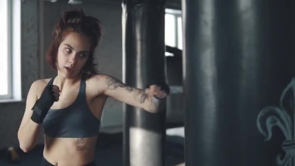 Atraente kickboxing mulher saco de treino de perfuração no estúdio de fitness. retrato de uma menina boxe no ginásio — Vídeo de Stock