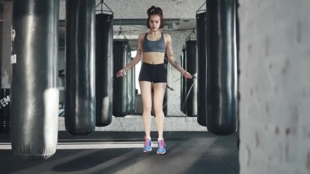 Ragazza atletica corda da salto. atleta in abbigliamento sportivo si allena in palestra. rallentatore — Video Stock