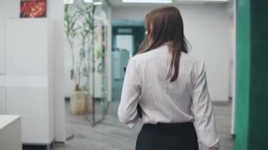 Genç çekici kadın office belgeleri için bir klasör ile etrafta dolaşıyor. Arkadan Görünüm
