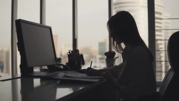 Jovem trabalha com documentos no final da noite no escritório. silhueta de uma mulher de negócios no local de trabalho — Vídeo de Stock