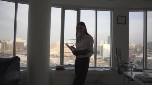 Business woman walking through an empty office with a folder for papers. woman working alone in the evening — Stock Video