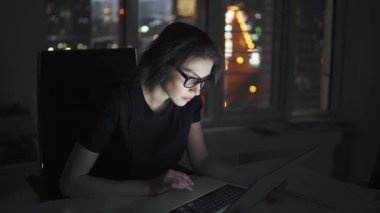 geç saatlere kadar ofiste serbest meslek. şehir ışıkları arka plan üzerinde bir laptop Kız bardaklarda çalışır