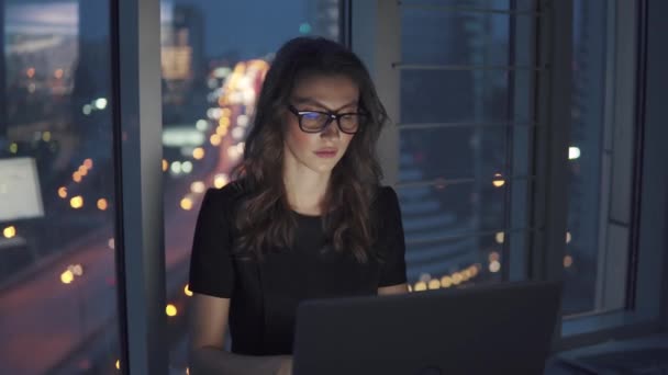 Retrato de una mujer de negocios en el fondo de la ciudad nocturna. la chica trabaja hasta tarde en la oficina — Vídeo de stock