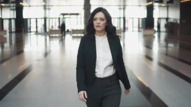 iş takım elbiseli genç bir kadın bir modern ofis binasının lobisinde yürür.