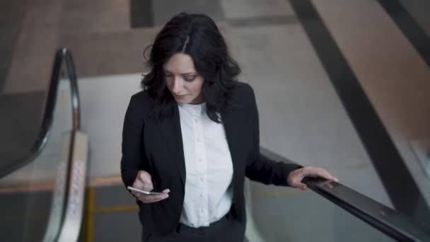 Affärskvinna klättrar på rulltrappan i lobbyn till en business kontorsbyggnad. — Stockvideo