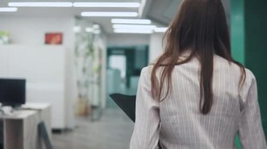 Genç çekici kadın office belgeleri için bir klasör ile etrafta dolaşıyor. Arkadan Görünüm