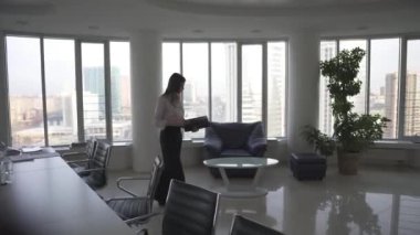iş kadını yavaşça ofis belgeleri okuyan etrafında yürüyüş. modern bir ofiste bir kızın silüeti.
