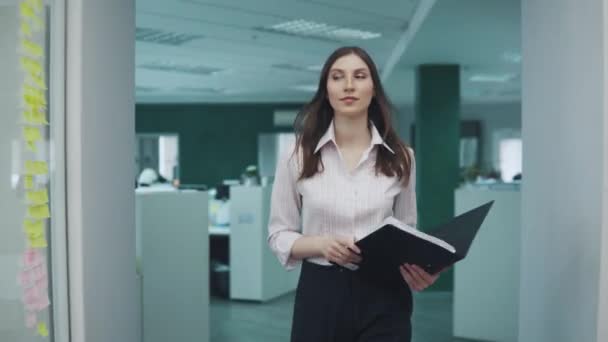 Magabiztos üzleti nő sétál az irodában folyosón. vonzó lány egy mappát a papírok diplomatatáskák egy találkozót. — Stock videók