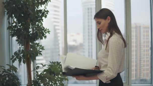 Retrato de uma rapariga no escritório. mulher jovem com uma pasta de documentos nas mãos — Vídeo de Stock