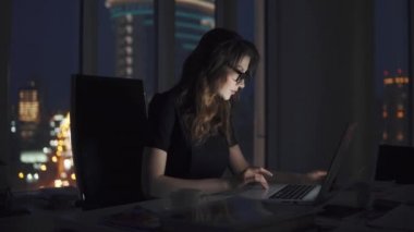 Genç iş kadını ofiste geç saatlere kadar çalışıyor. gece şehrin arka planda gözlük ile bir kız portre