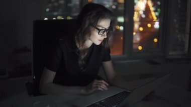 geç saatlere kadar ofiste serbest meslek. şehir ışıkları arka plan üzerinde bir laptop Kız bardaklarda çalışır