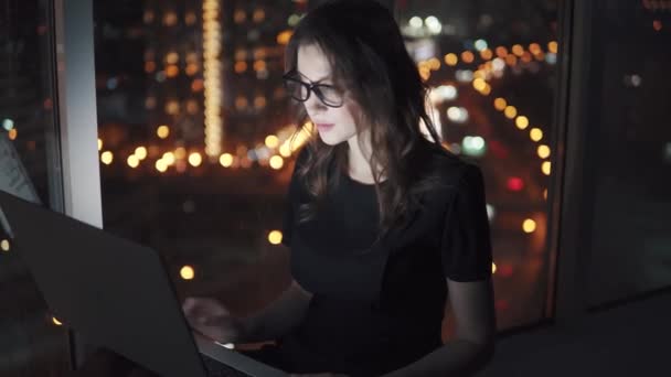 Jonge zakenvrouw in het licht van het scherm van een mobiele telefoon. meisje met een smartphone op de achtergrond bokeh van de nacht-stad. — Stockvideo