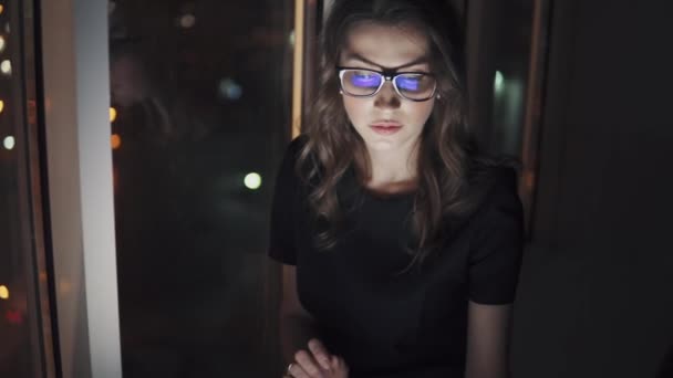 メガネと画面の反射。少女は、暗闇の中でスマート フォンを使用します。夜の街の背景に若い女性の肖像画 — ストック動画