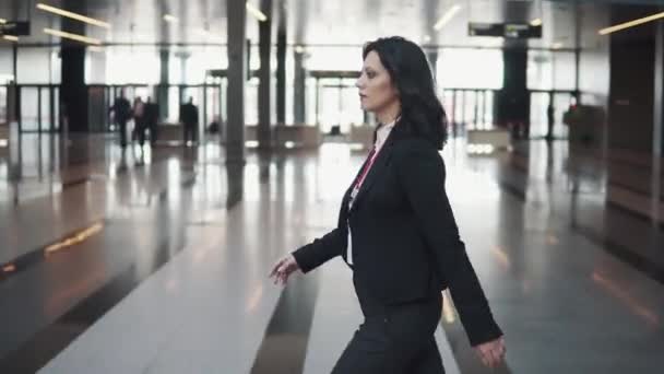 Ділова жінка швидко проходить через яскраве вестибюль офісної будівлі — стокове відео