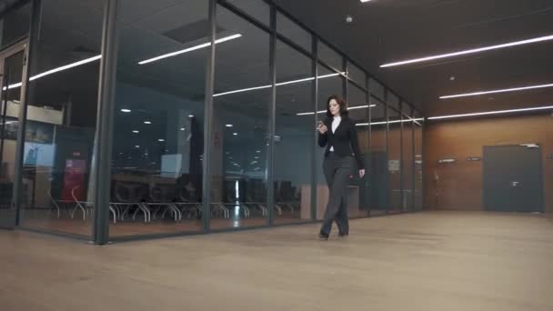 Junge Frau im Businessanzug läuft den Flur eines Bürogebäudes entlang. — Stockvideo
