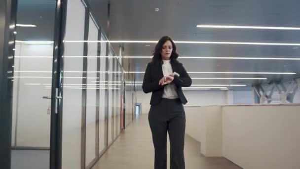 Уверенная деловая женщина пользуется мобильным телефоном. девушка в деловом костюме, проходящая через офисное здание . — стоковое видео