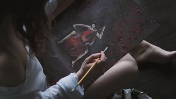A művész az otthoni padlón ülve képet fest. felülnézet — Stock videók