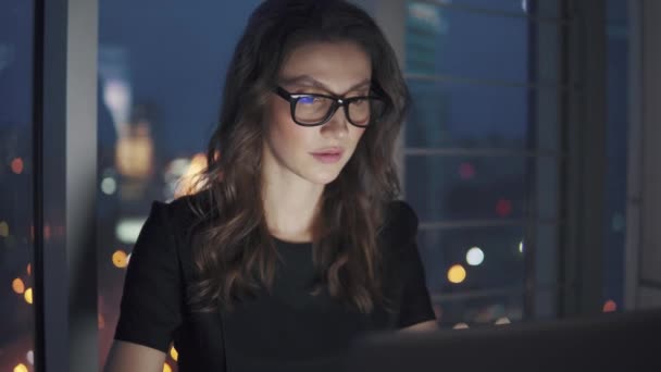 Крупним планом портрет ділової жінки на фоні нічного міста. дівчина працює пізно в офісі. відображення монітора в окулярах — стокове відео