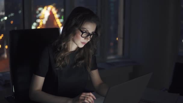 Giovane donna d'affari che lavora fino a tardi in ufficio. ragazza alla luce di un computer portatile di lavoro . — Video Stock