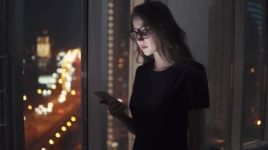 smartphone ekran ışığında genç bir kızın portresi. Kız bir cep telefonu gece şehrin arka planı kullanır