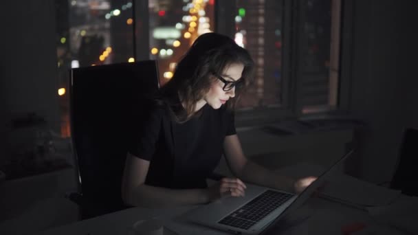 Mujer de negocios con gafas trabajando en una computadora en la noche. retrato de un joven especialista en el trabajo — Vídeo de stock