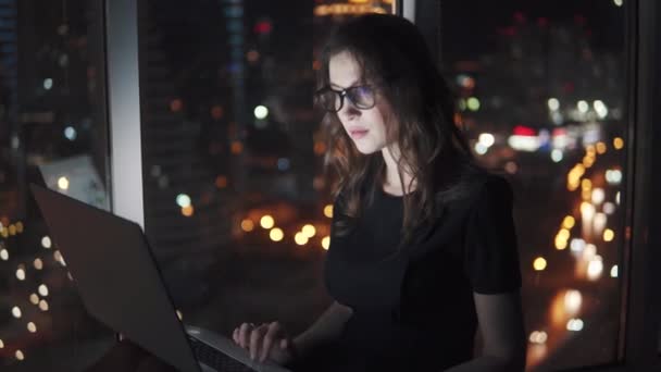 Jeune femme d'affaires à la lumière d'un écran de téléphone portable. fille avec un smartphone sur le fond bokeh de la ville de la nuit . — Video