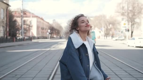 Vrolijk jong meisje zorgeloos wandelen in de straat en glimlachend. een jonge vrouw deelt haar goede humeur met anderen. — Stockvideo