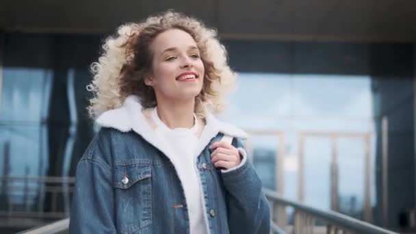 Gioia spensierata e divertimento. una giovane ragazza affascinante cammina per la strada e sorride ampiamente . — Video Stock