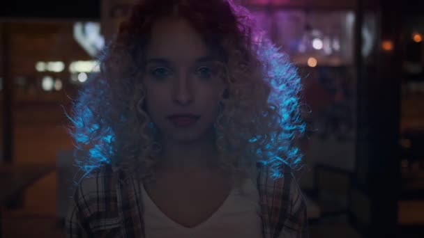 Retrato de una chica en un club nocturno. chica encantadora mirando y sonriendo a la cámara en los rayos de los focos — Vídeos de Stock