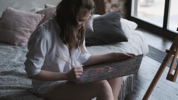 Malarz dziewczyna maluje obraz w domowym studiu. Artysta pracuje nad obrazem rano. — Wideo stockowe