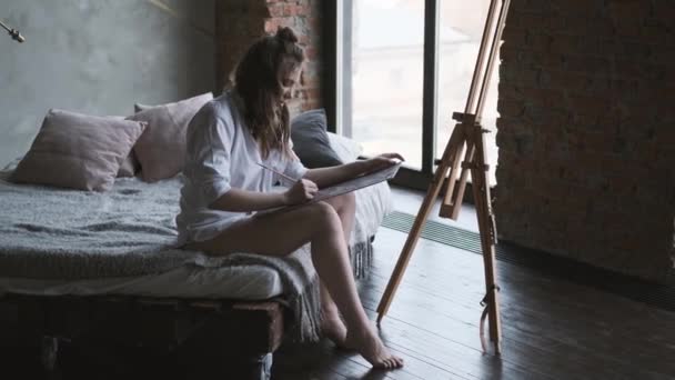 Pintor menina pinta um quadro no estúdio em casa. artista está trabalhando em uma pintura pela manhã . — Vídeo de Stock