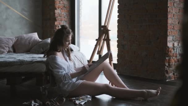 Porträtt konstnär på jobbet. flickan målar en bild av sittande på golvet i hemmastudion. — Stockvideo