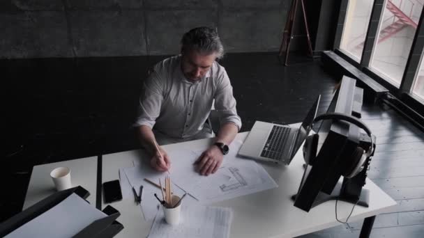 Мужчина-архитектор работает с документами и рисунками в офисе. Портрет успешного бизнесмена средних лет — стоковое видео