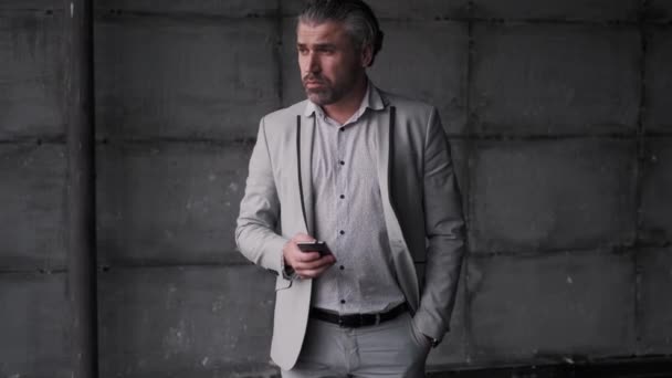 Το πορτρέτο ενός μεσήλικα άντρα με στολή. επιχειρηματίας κρατώντας ένα smartphone στα χέρια του. — Αρχείο Βίντεο