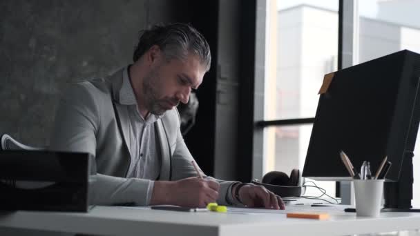 Geschäftsmann, der im Büro am Tisch sitzt. — Stockvideo