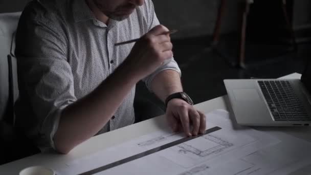 Мужчина среднего возраста работает с документами и рисунками, сидя за столом в офисе . — стоковое видео