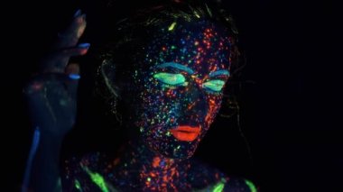 neon ışık bir kız portresi. koyu boya parıltı ile boyanmış yüz.