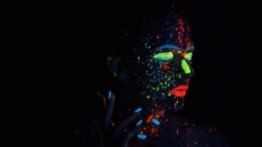 Yüzünde neon boya var. parlayan boya ile boyanmış bir kız portresi