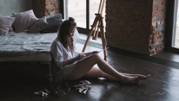 Dívčí umělecká díla sedící na podlaze v domácím studiu