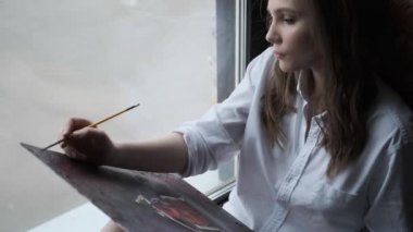 kız ressam fırçalar ile bir resim boyar. bir ev stüdyosunda sevimli bir kız portresi.